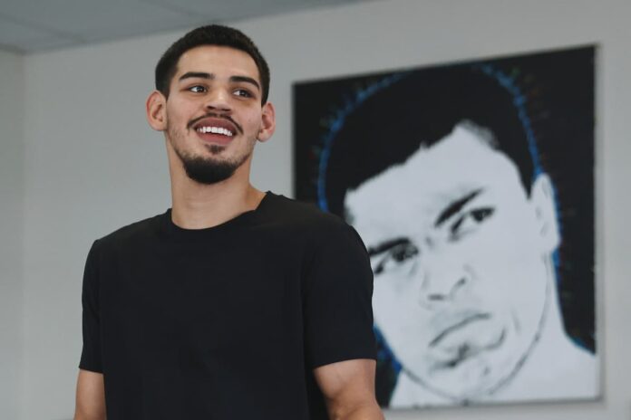 Diego Pacheco poses in front of the portrait of Muhammad Ali