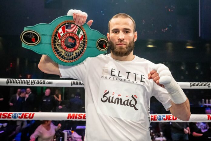 Arthur Biyarslanov holding his championship belt after defeating Mohamed Mimoune in a boxing match