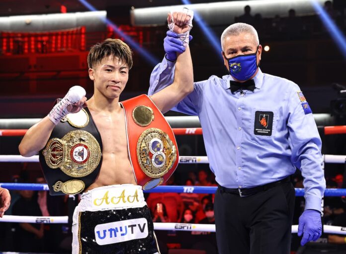 Referee Russell Mora raises the hand of boxer Naoya Inoue in victory